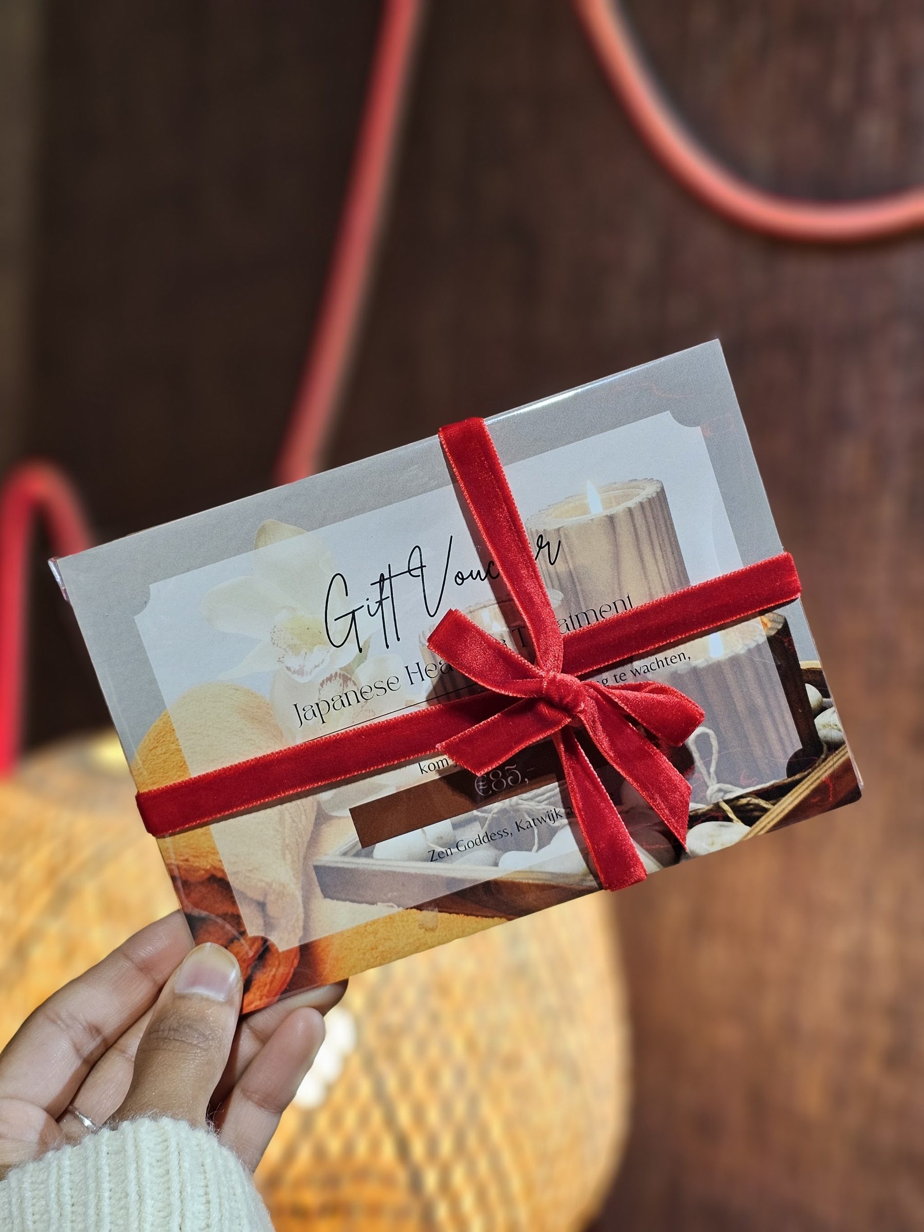 Een cadeaubon van Zen Goddess met een rood fluwelen lint