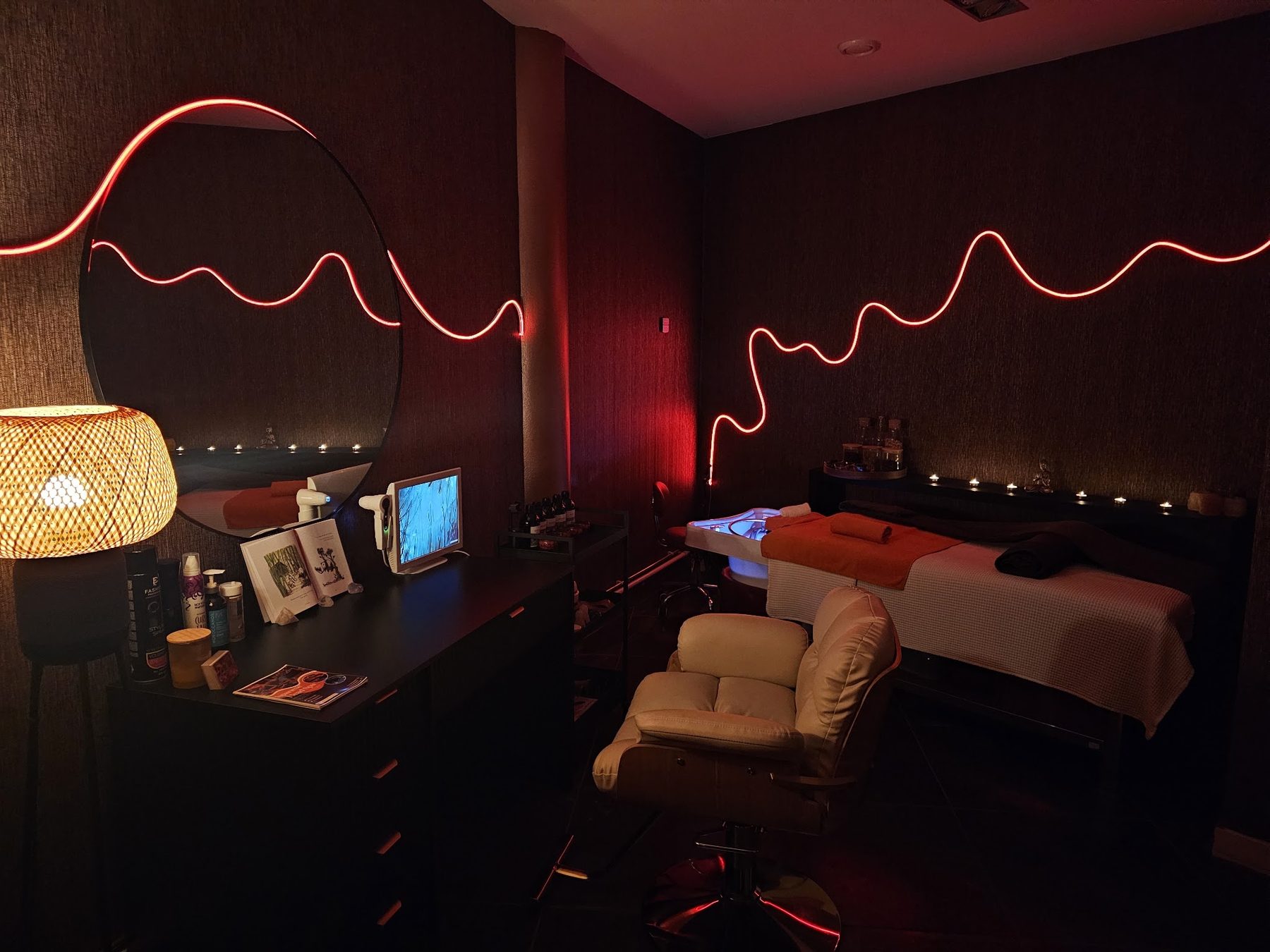 De behandelruimte van Zen Goddess met het rode neonlicht, de spa-stoel en de wasbak