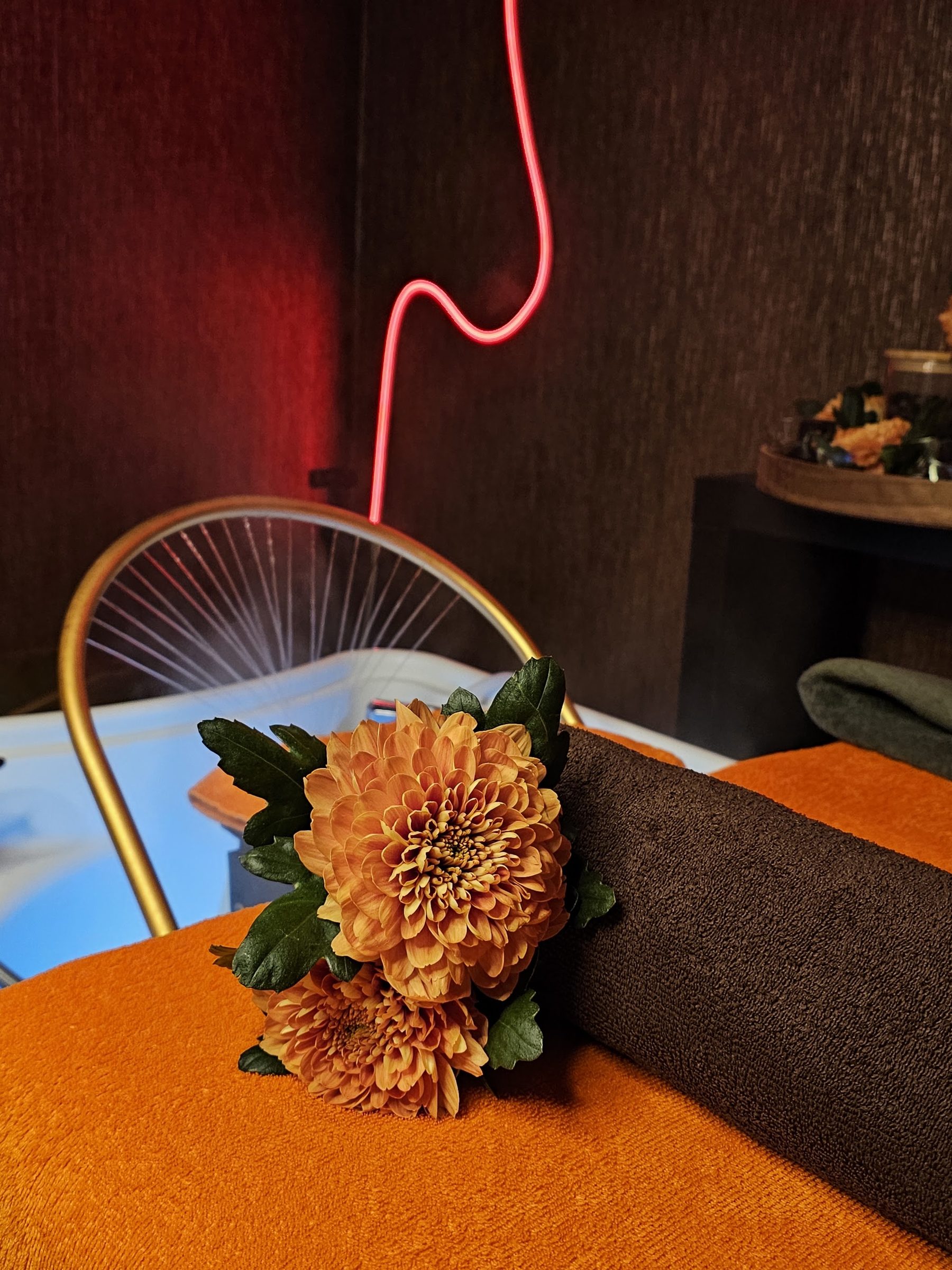 De gouden wasbak met oranje chrysanten en het rode neonlicht erachter